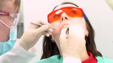 Bayan hasta onu diş bakımı kavramı bir dişçi ofisinde muayene için bir doktor ile. Medya. Koruyucu gözlük, diş hekimi sandalyede oturan genç bir kızı ziyaret.