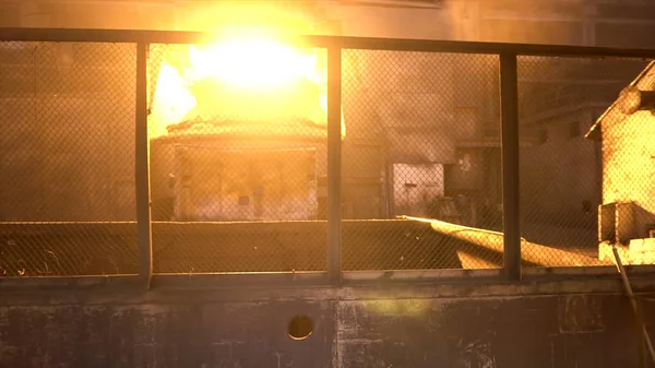Metal steel worker in special uniform passing through metallurgical shops with bif metal furnace. Stock footage. Working at metal steel plant.