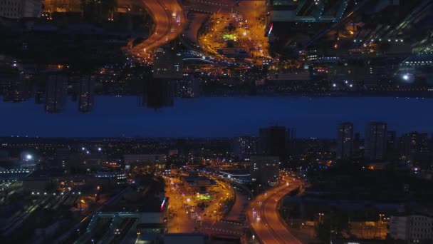 Vista aérea nocturna de una gran ciudad y hermosas luces, concepto de vida nocturna, efecto espejo horizonte. Medios. Paisaje urbano nocturno con carreteras iluminadas y coches en movimiento, tema de inicio . — Vídeos de Stock