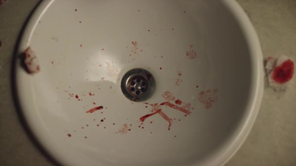 Nahaufnahme eines weißen Waschbeckens mit Blutflecken und blutigen Wattestäbchen. Archivmaterial. jemand wirft sie in eine Spüle — Stockvideo