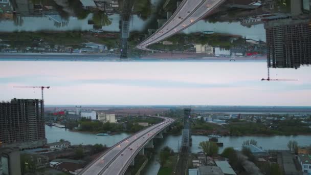 Blick auf die Stadt am frühen Morgen mit Flussbrücke, unvollendetem Gebäude und vielen grünen Bäumen, Spiegelhorizonteffekt. Medien. grauer Morgen in der Stadt mit türkisfarbenem Fluss, Schiffen und Brücke. — Stockvideo