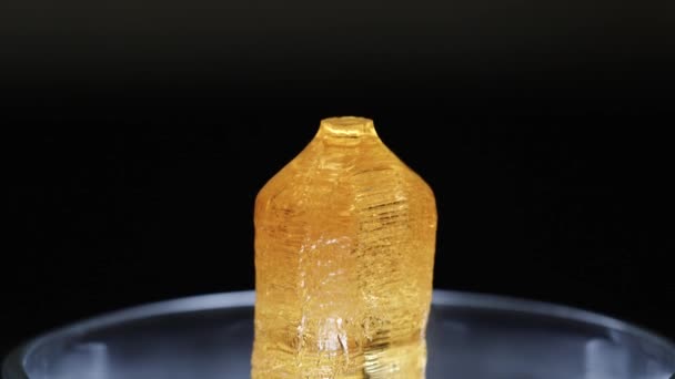 Крупним планом прозорий жовтий мінерал, що стоїть у скляному лабораторному посуді на чорному тлі. Стокові кадри. Хімічні експерименти — стокове відео