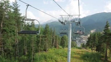 Yaz aylarında mavi bulutlu gökyüzüne karşı iğne yapraklı ağaçlarla kaplı güzel dağlarda teleferiğe bakın. Stok görüntüleri. Güzel dağ manzarası