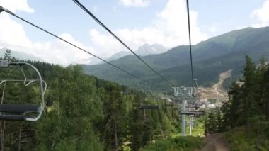 Yaz aylarında mavi bulutlu gökyüzüne karşı iğne yapraklı ağaçlarla kaplı güzel dağlarda teleferiğe bakın. Stok görüntüleri. Güzel dağ manzarası