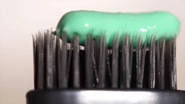 Extreme close-up van een grijze tandenborstel met groene tandpasta op een witte achtergrond, tandheelkundige zorg concept. Media. De borstels van de tandenborstel met verse tandpasta. — Stockfoto