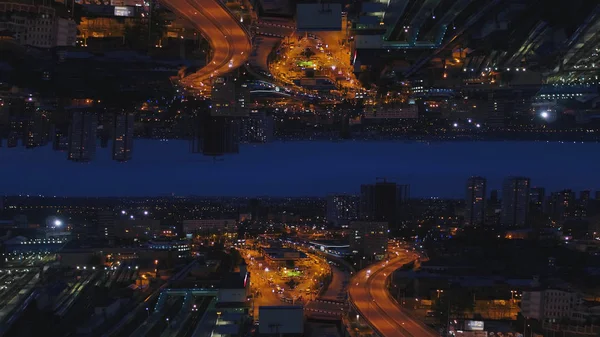 Aerial night view of a big city and beautiful lights, night life concept, mirror horizon effect. Media. Night cityscape with lighted roads and moving cars, inception theme. — Stock Photo, Image