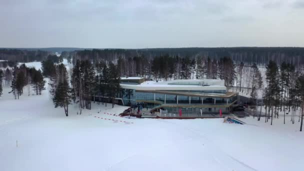 Blick von oben auf das Winter-Erholungszentrum. Filmmaterial. schöne Basis des Wintersportortes umgeben von Bäumen und versammelten Touristen und Skifahrer — Stockvideo