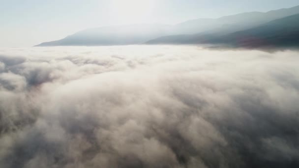 Vista aérea de nuvens e paisagem sob eles. Atingido. Vista superior das nuvens sob o céu. Sob as nuvens disparadas de um voo de pássaros, o sol brilha nas nuvens — Vídeo de Stock