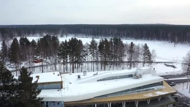 Вид сверху на центр зимнего отдыха. Запись. База зимнего курорта окружена деревьями и собирает туристов и лыжников — стоковое видео