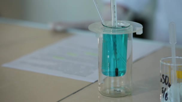 実験室での実験のためにビーカーの温度計を使用しなさい。試験管内の液体中の温度計 — ストック動画