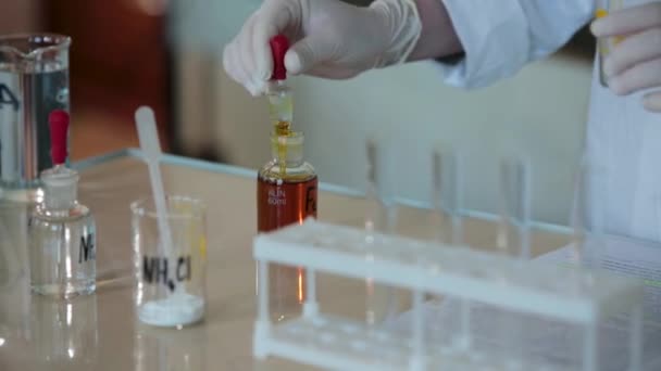 Gros plan d'un scientifique égouttant un liquide rouge dans une éprouvette. Verser le liquide dans le tube depuis la pipette — Video