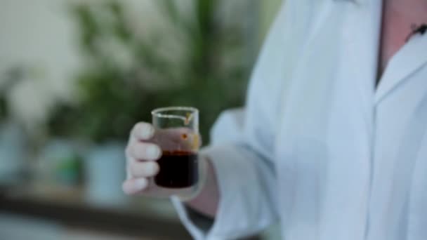 Bilim adamı el bir bilim araştırma laboratuvarında bir deney için sıvı ile bilimsel bir silindir içine bir laboratuvar cam test tüpü kimyasal bir çözüm dökme — Stok video
