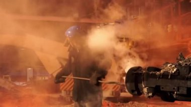 Metalurji fabrikasında üniforma Temizleme fırını giyen bir işçi için yakın. Stok görüntüleri. Çelik üretim fabrikasında çalışma sürecinde kask furnaceman.