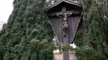 Çarmıha gerilmiş İsa 'nın tahta simgesi. - Sanat. Çarmıha gerilen İsa 'nın ahşap heykeli yeşil sık ağaçlar ve çalılar arasında duruyor.
