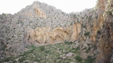 Gökyüzünün arka planında uçurumun alt görünümü. Madde. Yürüyerek yeşillik ve gökyüzünün arka planda seyrek çalılar ile kayalık dağ çevrili