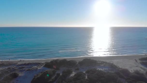 Blick von oben auf Strand mit blauem Meer und Sonne am Horizont. Kunst. Menschen am Strand entspannen sich und genießen den blauen Horizont des Berührens von Meer und Himmel und die Reflexion der Sonne auf dem Wasser — Stockvideo