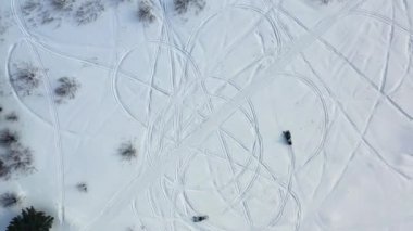 Kar motosikletleri sürme üst görünümü. Görüntü. Güneşli bir günde karda ayak izi bırakan daire içinde sürüş iki kar motosikleti üst görünümü