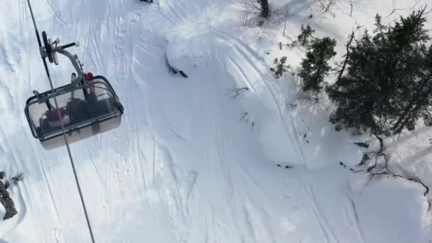 Kışın kabinli teleferiğin en iyi görünümü. Görüntü. Kayak merkezinde kış aktiviteleri. Kışın yeşil köknar ağaçları ile alt kayak izi ile teleferik — Stok video