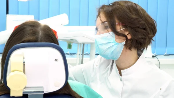 Achteraanzicht van de tandarts de behandeling van tanden aan vrouw patiënt in kliniek, tandheelkundige zorg concet. Media. Vrouwelijke professionele arts stomatologist op het werk met tandheelkundige apparatuur. — Stockfoto