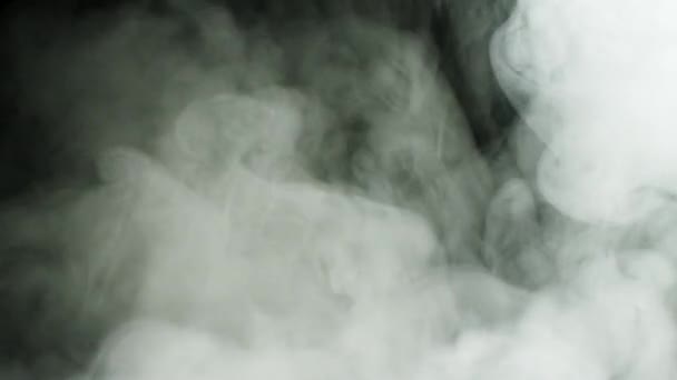 Магнітна товста димчаста хмара повільно рухається на чорному тлі. Стокові кадри. Білий туман тече в темряві перед камерою . — стокове відео