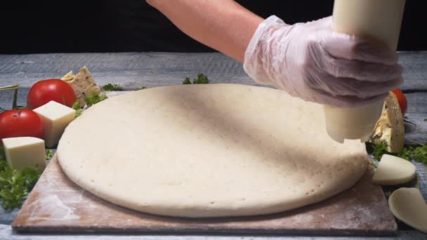 Na dřevěné desce s různými ingrediencemi je třeba zavřít ruce, které zakrývající Pizza těsto s bílou omáčkou. Rámeček. Vynikající příprava pizzy — Stock video