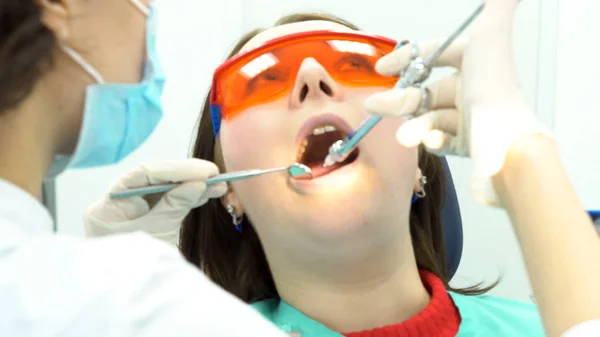 Dentist holding a syringe and anesthetizing his patient. Media. Female patient with open mouth receives an injection at the dentist office, medicine concept.