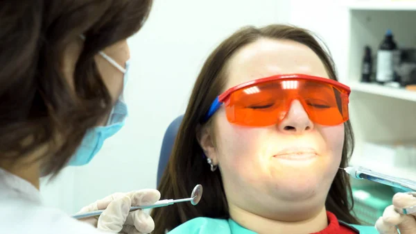 Closeup portrait of a girl scared of needles and syringes at dentist visit. Media. Female dentist making anaesthetic injection to scared female patient.