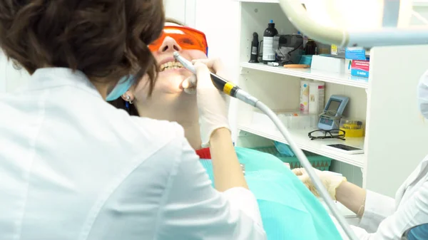 Professional dental cleaning of female patient teeth at dental clinic, medicine concept. Media. Women dentists doing the procedure of teeth cleaning and polishing at the dentist office.