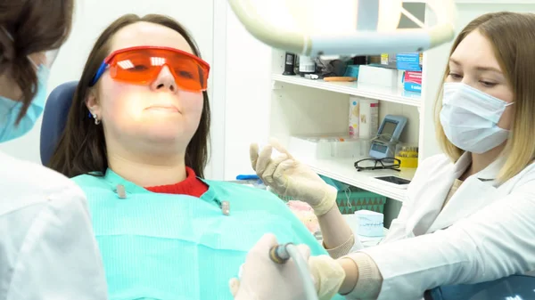 Professionele tandheelkundige reiniging van vrouwelijke patiënt tanden bij Dental Clinic, Medicine concept. Media. Vrouwen tandartsen doen de procedure van tanden schoonmaken en polijsten bij het tandarts Bureau. — Stockfoto