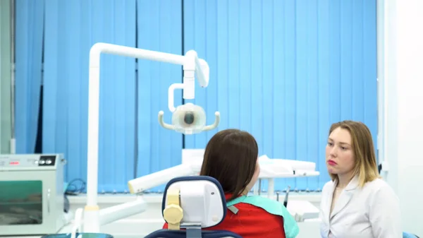 De arts bereidt zich voor op de aankomende procedure en draagt het beschermende masker met zijn assistent die met de patiënt praat. Media. Young Doctors aan het werk bij Dental Clinic, Medicine concept. — Stockfoto