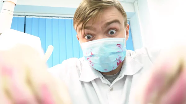 Η πρώτη όψη ενός νεαρού οδοντίατρου με μάσκα πλησιάζει με τα εργαλεία. Media. Νέος γιατρός στέκεται πάνω από τον ασθενή, κοιτάζοντας την κάμερα. — Φωτογραφία Αρχείου