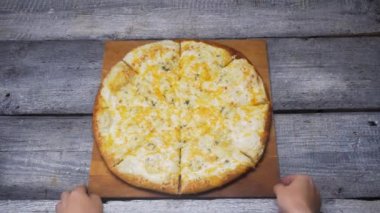 Sıcak dört peynir lezzetli pizza ahşap gri panoları arka plan üzerinde bir tepsi üzerinde yatıyor. Çerçeve. Ahşap bir yüzeyden pizza daire ile bir tahta koyarak eller için kapatın.