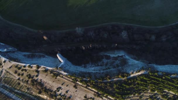 Top view of breathtaking cliff with white slope near green meadow and country road. Shot. Aerial for rock cliff near the field with green grass and growing pine trees. — Stock Video