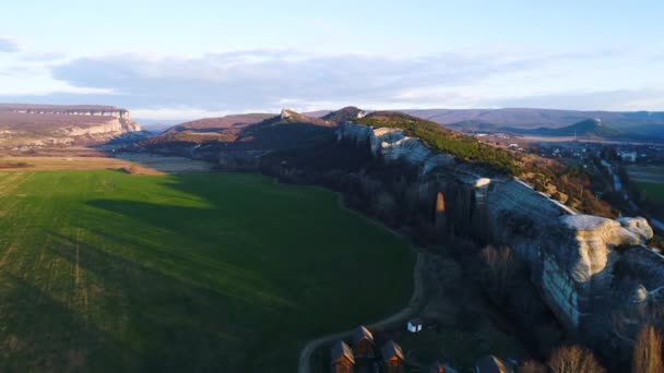 Top view of mountain landscape with green fields in evening sun. Shot. Beautiful mountain area with stone rock green lush field at foot of mountain horizon with cloudy sky — Stock Video