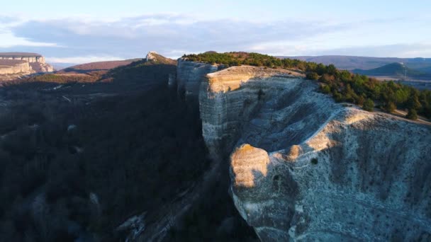 Vista superior del acantilado de piedra con arbusto verde en el pico. Le dispararon. Hermoso paisaje de montaña con sombra de fundición de roca del sol de la noche y separando los lados oscuros y claros — Vídeos de Stock