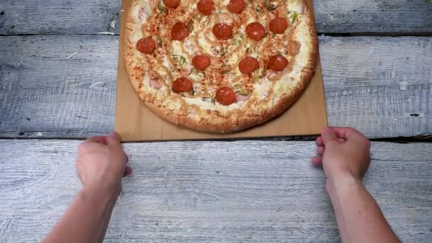 Välsmakande pizza på träbricka på vit bordsbakgrund. Ram. Man flyttar nybakad pizza med pepperoni på träbricka — Stockvideo