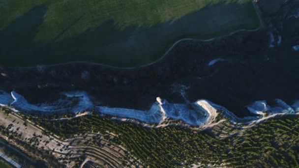 Bela vista superior do penhasco da montanha coberto com árvores de coníferas perto do campo verde de um lado e rodovia do outro. Verão nas montanhas — Vídeo de Stock