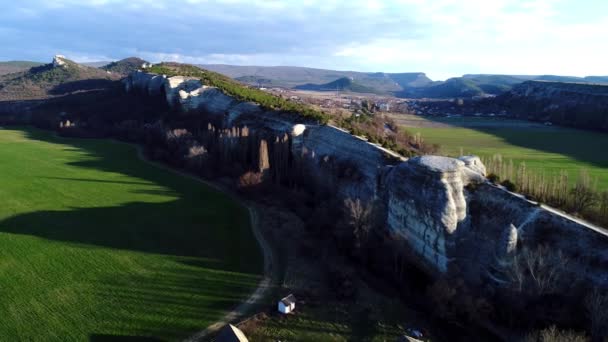 Toppen utsikt över den vackra naturstens muren. Skott. Rock med gröna grönskande fält till fots och bergslandskap på horisonten i morgonsolen — Stockvideo