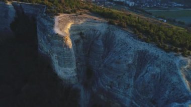 Karayolu ve arka planda binalar ile üst kozalaklı ağaçlar ile gri dağ uçurum yüzeyinin yakın çekim görünümü. Görüntü. Güzel dağlar manzara