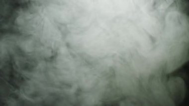 Duman bulutu siyah arka planda yayılır. Stok görüntüleri. Akarsularda akan ve siyah izole arka plan üzerinde yayılan yoğun kalın beyaz duman bulutları