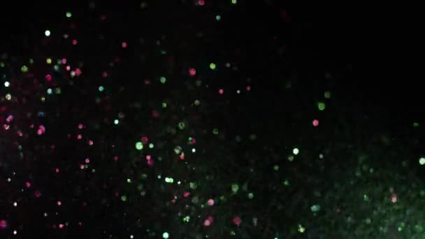 Splash di brillantini brillanti di colore su sfondo nero. Filmati delle scorte. Particelle colorate brillanti e scintillanti durante spruzzi e dispersioni su sfondo nero isolato — Video Stock