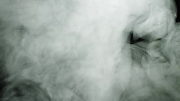 Rauchwolken breiten sich auf schwarzem Grund aus. Archivmaterial. dichte, weiße Rauchwolken, die in Strömen fließen und sich über einen isolierten schwarzen Hintergrund ausbreiten — Stockvideo
