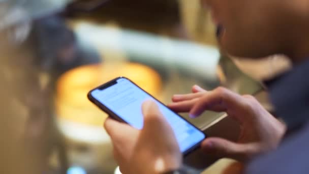 Primer plano de un hombre que sostiene el dispositivo y la lectura del texto en la pantalla, concepto de tecnologías modernas. Acciones. Un hombre con camisa azul oscuro y reloj negro en la muñeca sosteniendo su smartphone . — Vídeos de Stock