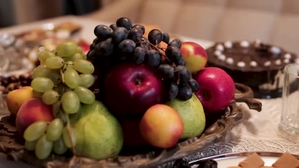 Закройте традиционный стол яблоками, виноградом, горохом и различными восточными сладостями с орехами, едой и концепцией праздника. На складе. Вкусные блюда с фруктами и сладостями . — стоковое видео