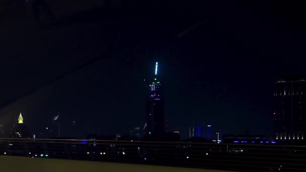사이스크러의 빛나는 불빛에 움직이는 자동차의 창에서 밤 도시 풍경. 주식. 많은 현대적인 건물이있는 밤에 아름다운 메가 폴리스. — 비디오
