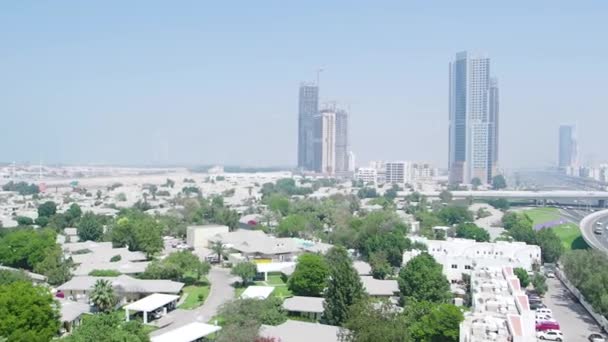 Вид зверху в Дубаї з хмарочосами, невеликими будинками, дорогами і деревами. Запас. Антена для сучасного міста в Об'єднаних Арабських Еміратах з відомим готелем Бурдж аль-Араб в тумані на фоні. — стокове відео