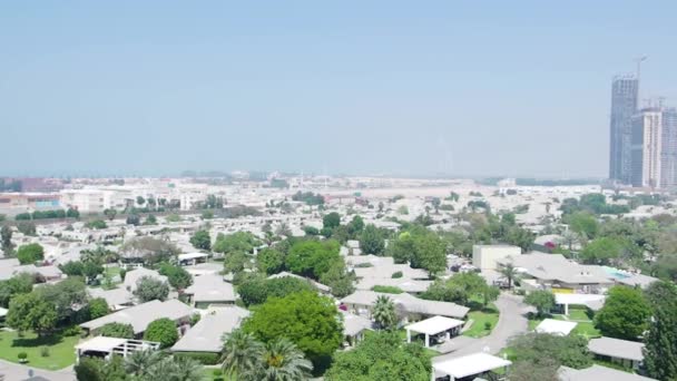 Vista de cima para o Dubai com arranha-céus, pequenas casas, estradas e árvores. Estoque. Aéreo para a cidade moderna nos Emirados Árabes Unidos com um famoso hotel Burj Al Arab no nevoeiro no fundo . — Vídeo de Stock