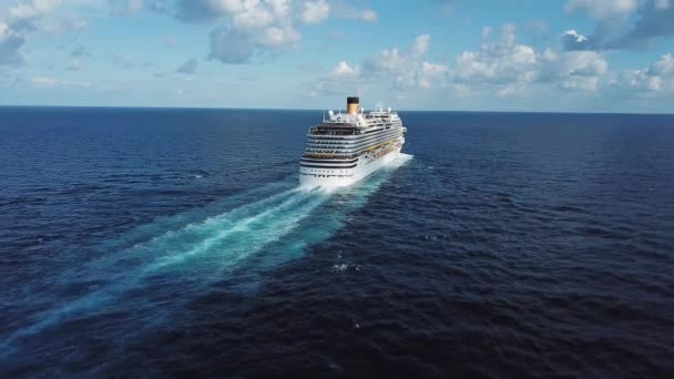 Indietro della nave da crociera e la sua bella scia sulla superficie blu del mare, paesaggio marino. Azioni. Veduta aerea di una bella nave da crociera bianca in una giornata di sole su sfondo cielo nuvoloso blu . — Video Stock