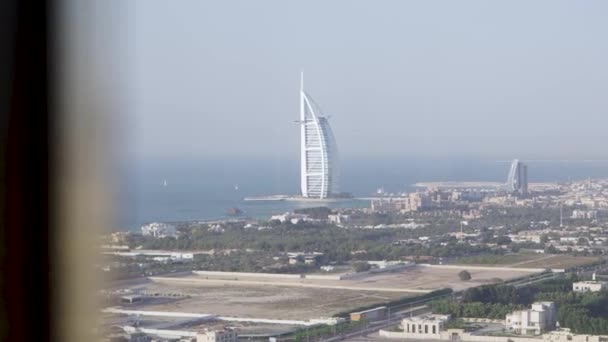 Malowniczy widok na Dubajskie miasto i błękitne z okna pokoju hotelowego. Stock. Wspaniały widok na luksusowy hotel Burj Al Arab. — Wideo stockowe