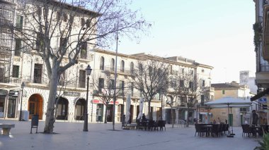 Kafeler ve akşamları yürüyen insanlar ile şehir meydanı. Madde. Sonbaharda kafe ve ağaçlarla Avrupa evlerinin arka planında yürüyen insanların kentsel görünümü